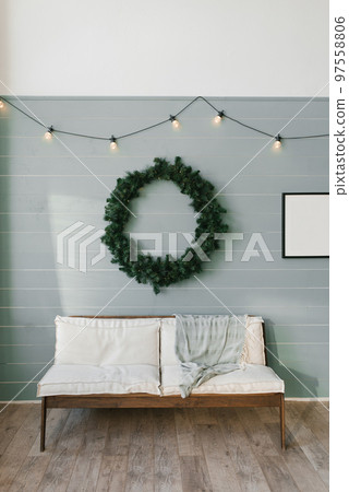Wooden sofa with white soft pillows and a large Christmas wreath on the wall, lined with clapboard 97558806