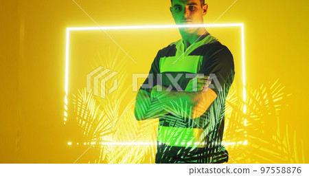 Midsection of caucasian rugby player with arms crossed standing over illuminated rectangle and plant Midsection of caucasian rugby player with arms crossed standing over illuminated rectangle and plant 97558876
