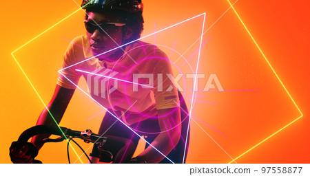 Biracial female cyclist wearing glasses and helmet riding bike over illuminated geometric shapes 97558877