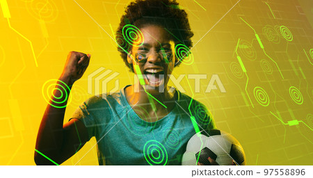 Biracial soccer player with brazilian flag's face paint screaming over illuminated circles and lines Biracial soccer player with brazilian flag's face paint screaming over illuminated circles and lines 97558896