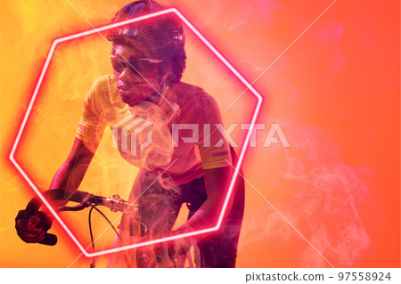 Hexagon neon over dedicated african american cyclist riding bicycle against orange background Hexagon neon over dedicated african american cyclist riding bicycle against orange background 97558924