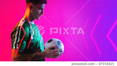 Composite of young caucasian player holding soccer ball with abstract neon pattern, copy space Composite of young caucasian player holding soccer ball with abstract neon pattern, copy space 97558925