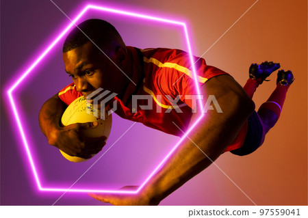 Hexagon neon over african american young rugby player jumping against colored background Hexagon neon over african american young rugby player jumping against colored background 97559041