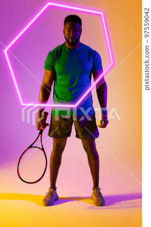 Hexagon neon over confident african american tennis player with racket against colored background 97559042