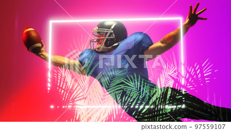 American football player catching ball while jumping by illuminated rectangle and plants 97559107