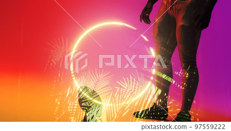 Low section of american football player with ball standing by illuminated plants and circle 97559222