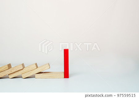 One red domino stands, and other wooden dominoes fall in a row.  97559515