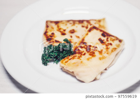 thin pancakes with meat filling and a sprig of parsley on a white plate 97559619