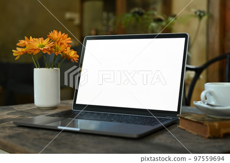 Laptop computer with white empty screen, coffee cup and books on rustic wooden table 97559694