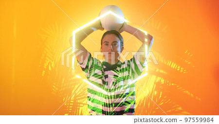 Caucasian female player throwing ball over illuminated plants and hexagon on orange background Caucasian female player throwing ball over illuminated plants and hexagon on orange background 97559984