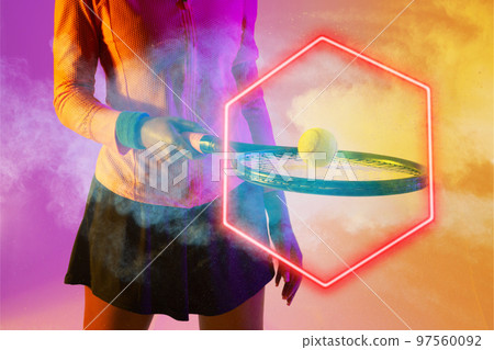 Midsection of african american female tennis player with ball on racket by illuminated hexagon 97560092