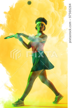 Full length of african american female tennis player hitting ball with racket over smoky background Full length of african american female tennis player hitting ball with racket over smoky background 97560264