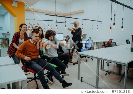 Team building and office fun. Young cheerful businesspeople in smart casual wear having fun while racing on office chairs and smiling. Team building and office fun. Young cheerful businesspeople in smart casual wear having fun while racing on office chairs and smiling. 97561218