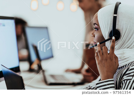 African American muslim woman with hijab and headset working as customer support in a modern office. African American muslim woman with hijab and headset working as customer support in a modern office. 97561354