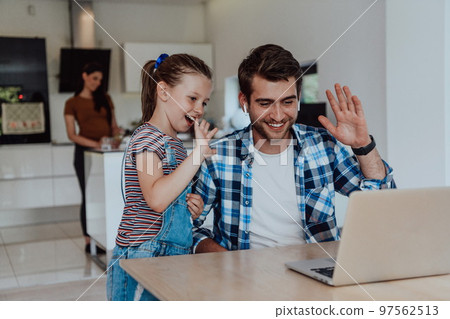 Father and daughter in modern house talking together on laptop with their family during holidays. The life of a modern family 97562513