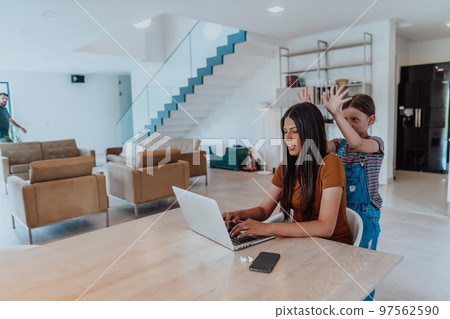 Mother with her daughter talking on laptop with family and friends while sitting in modern living room of big house Mother with her daughter talking on laptop with family and friends while sitting in modern living room of big house 97562590