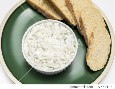 Traditional homemade greek yogurt sauce Tzatziki, tarator in white bowl, made of grated cucumbers, sour cream yogurt,olive oil,garlic,herbs on plate with sliced bread, white background.Horizontal Traditional homemade greek yogurt sauce Tzatziki, tarator in white bowl, made of grated cucumbers, sour cream yogurt,olive oil,garlic,herbs on plate with sliced bread, white background.Horizontal 97564182