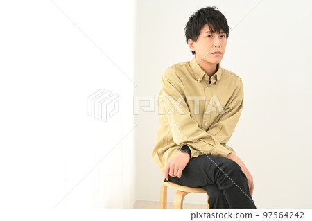Young man portrait sitting on a chair indoors 97564242