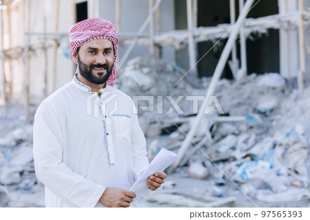 Arab muslim adult engineer business male portrait standing with floor plan at construction site Arab muslim adult engineer business male portrait standing with floor plan at construction site 97565393