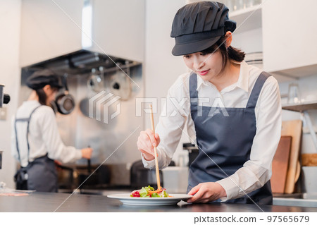 Two female staff working in a restaurant kitchen Two female staff working in a restaurant kitchen 97565679