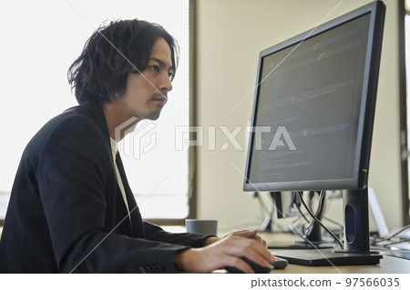 A man in his early 30s working on a desktop computer 97566035