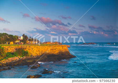 Galle Fort panorama with old walls in sunset orange light against blue sky with pink clouds, ocean in background. Largest city fortress and port of Sri Lanka - popular tourist destination. 97566230