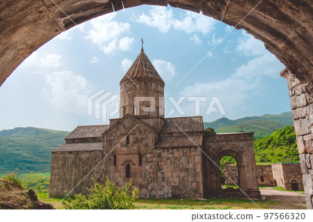 Tatev ancient monastery low view from arch. Armenia best famous travel location. Popular tourist destination. Old medieval church architecture. Mountain green hills in background. Travel, tourism Tatev ancient monastery low view from arch. Armenia best famous travel location. Popular tourist destination. Old medieval church architecture. Mountain green hills in background. Travel, tourism 97566320