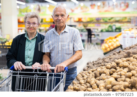 mature spouses chooses potato in vegetable section of supermarket 97567225