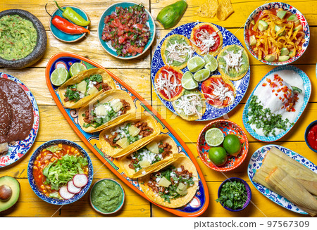 Mexican festive food for independence day independencia - chiles en nogada, tacos al pastor, chalupas pozole, tamales, chicken with mole poblano sauce. Yellow background. 97567309