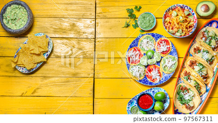 Mexican festive food for independence day independencia - chiles en nogada, tacos al pastor, chalupas pozole, tamales, chicken with mole poblano sauce. Yellow background. Mexican festive food for independence day independencia - chiles en nogada, tacos al pastor, chalupas pozole, tamales, chicken with mole poblano sauce. Yellow background. 97567311