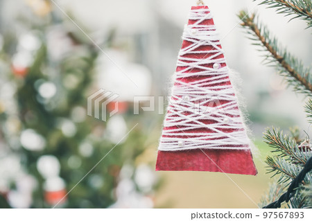 Red wool and paper handmade decoration on Christmas tree outdoor. Diy yarn crafts creative ideas for children. Environment, reuse, recycle, upcycling and zero waste concept. Selective focus Red wool and paper handmade decoration on Christmas tree outdoor. Diy yarn crafts creative ideas for children. Environment, reuse, recycle, upcycling and zero waste concept. Selective focus 97567893