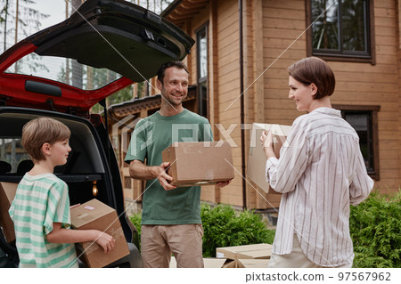 Happy family unloading boxes moving into new house in nature 97567962