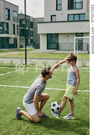 Loving father and son playing football together at outdoor court Loving father and son playing football together at outdoor court 97567983
