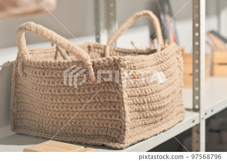 square shape jute knitted basket for natural storage on a shelf. eco knit item, hobby and leisure. natural home interior design. square shape jute knitted basket for natural storage on a shelf. eco knit item, hobby and leisure. natural home interior design. 97568796