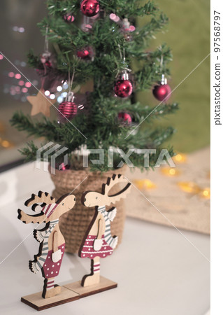 christmas tree decorated with viva magenta colored balls. wooden elks decor in trendy palette of 2023. vertical. holiday house decoration. christmas tree decorated with viva magenta colored balls. wooden elks decor in trendy palette of 2023. vertical. holiday house decoration. 97568797