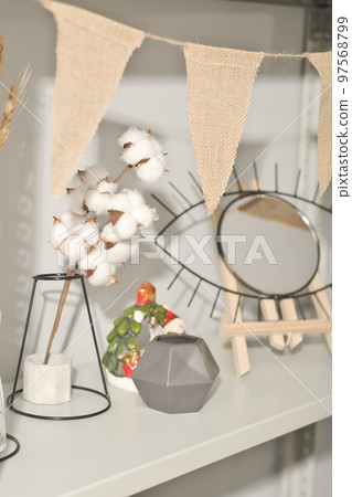 natural eco home decor on a shelf. cotton buds, concrete vase and eye shaped mirror on wooden stand. cotton bunting in beige unbleached color natural eco home decor on a shelf. cotton buds, concrete vase and eye shaped mirror on wooden stand. cotton bunting in beige unbleached color 97568799