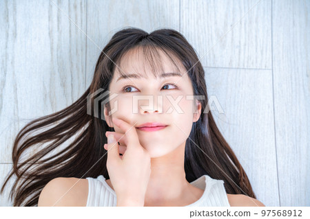 Young woman in tank top lying on flooring Young woman in tank top lying on flooring 97568912