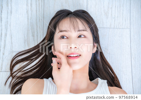 Young woman in tank top lying on flooring Young woman in tank top lying on flooring 97568914