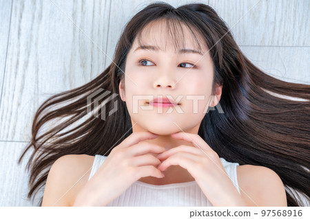 Young woman in tank top lying on flooring Young woman in tank top lying on flooring 97568916