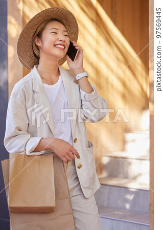 Asian woman, shopping bags or phone call in city for retail networking, urban luxury sales or clothing boutique buying. Smile, happy or fashion customer with gifts on mobile communication technology 97569445