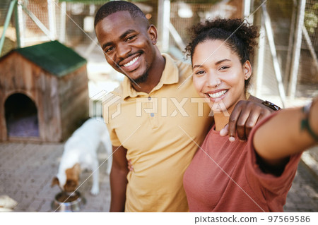 Love, dog or couple of friends take a selfie at an animal shelter or adoption center for homeless dogs. Pets, face portrait or black woman with a fun black man taking pictures as a happy black couple Love, dog or couple of friends take a selfie at an animal shelter or adoption center for homeless dogs. Pets, face portrait or black woman with a fun black man taking pictures as a happy black couple 97569586