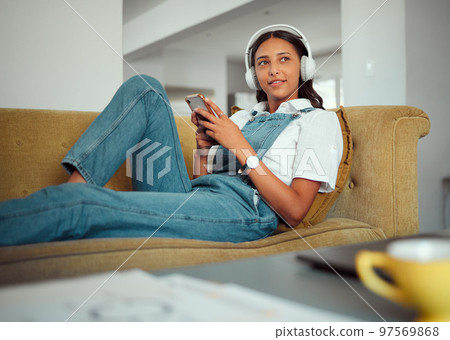 Relax, phone and woman on a sofa with music, radio and online entertainment in a living room, happy and content. Podcast, student and girl with smartphone on a couch, rest and break in Brazil home Relax, phone and woman on a sofa with music, radio and online entertainment in a living room, happy and content. Podcast, student and girl with smartphone on a couch, rest and break in Brazil home 97569868