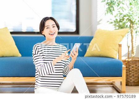 A woman operating a smartphone in the living room. 97570189