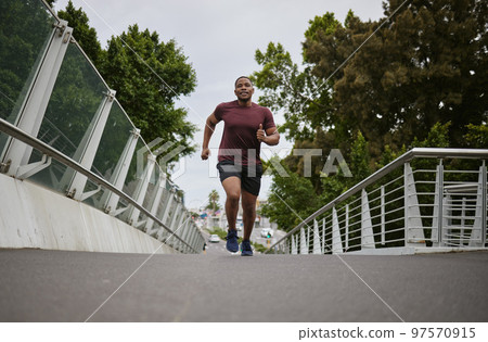 Black man running on bridge in city for fitness, exercise and healthy goals, sports wellness and marathon workout. Urban runner, cardio and training to lose weight with power, action and motivation Black man running on bridge in city for fitness, exercise and healthy goals, sports wellness and marathon workout. Urban runner, cardio and training to lose weight with power, action and motivation 97570915