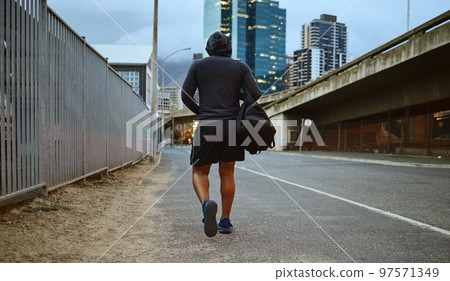 Fitness, black man and walking on city street after running, exercise and gym workout with a hoodie at night. Back of a male athlete in urban Miami for a walk and cardio training with a duffle bag Fitness, black man and walking on city street after running, exercise and gym workout with a hoodie at night. Back of a male athlete in urban Miami for a walk and cardio training with a duffle bag 97571349