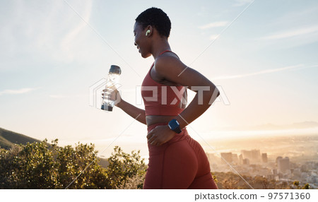 Workout, black woman or sunset with runner training, exercise for wellness, health or hydration. African American female, lady or athlete with water bottle, practice for marathon or fitness in nature Workout, black woman or sunset with runner training, exercise for wellness, health or hydration. African American female, lady or athlete with water bottle, practice for marathon or fitness in nature 97571360