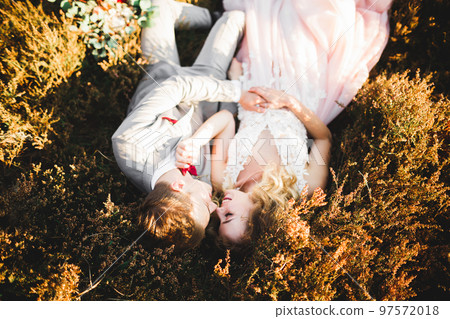 Beautiful bride and groom embracing and kissing on their wedding day outdoors 97572018