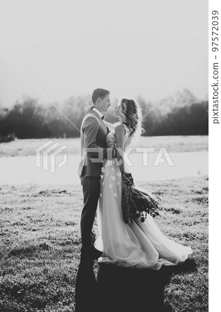 Beautifull wedding couple kissing and embracing near the shore of a mountain river with stones 97572039