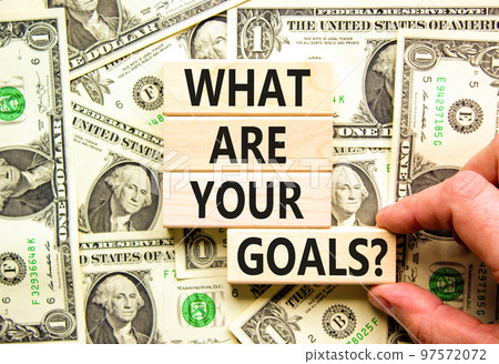What are your goals symbol. Concept words What are your goals on wooden blocks. Beautiful background from dollar bills. Businessman hand. Business psychological what are your goals concept. Copy space What are your goals symbol. Concept words What are your goals on wooden blocks. Beautiful background from dollar bills. Businessman hand. Business psychological what are your goals concept. Copy space 97572072
