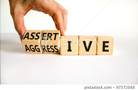Aggressive or assertive symbol. Businessman turns wooden cubes, changes the word Aggressive to Assertive. Beautiful white background, copy space. Business, psychological aggressive assertive concept. Aggressive or assertive symbol. Businessman turns wooden cubes, changes the word Aggressive to Assertive. Beautiful white background, copy space. Business, psychological aggressive assertive concept. 97572088